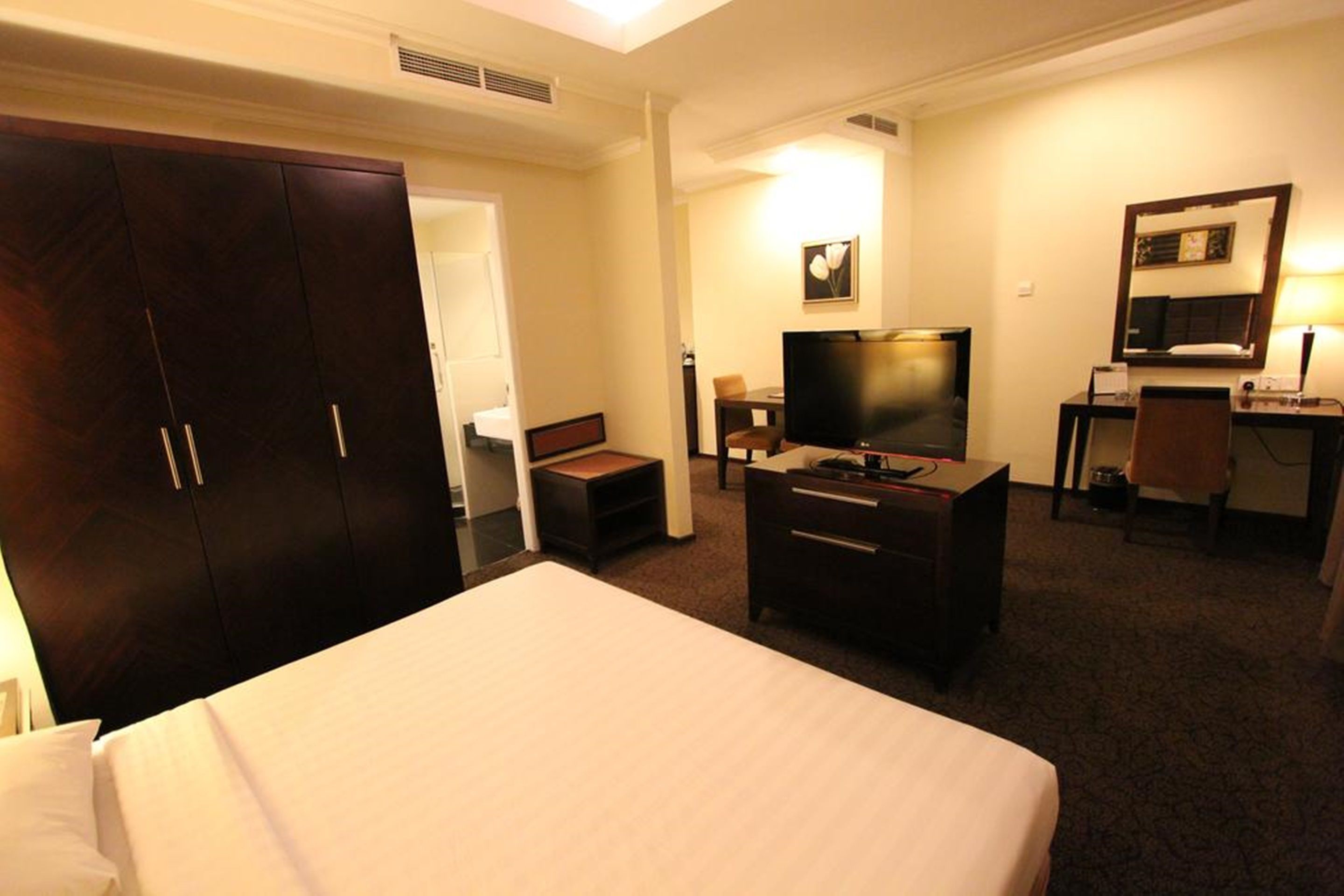 Una habitación de hotel con una cama grande, un escritorio con una silla, un televisor y un armario.