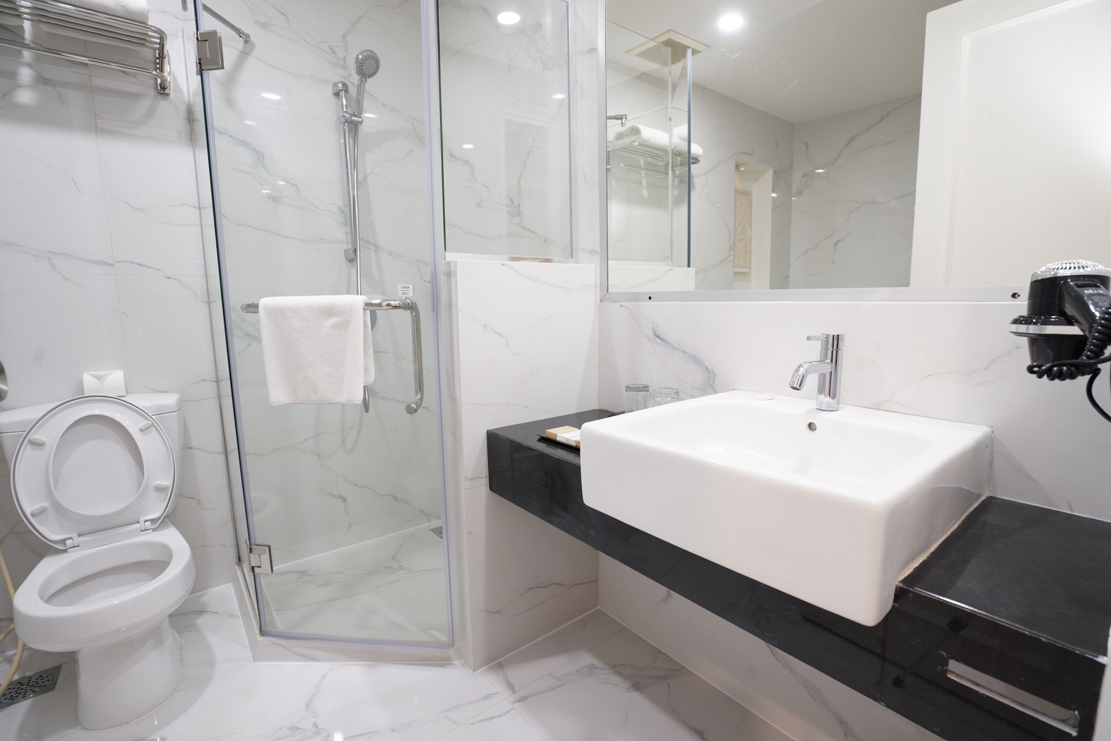 A modern bathroom with a glass-enclosed shower, a white sink, and a toilet.