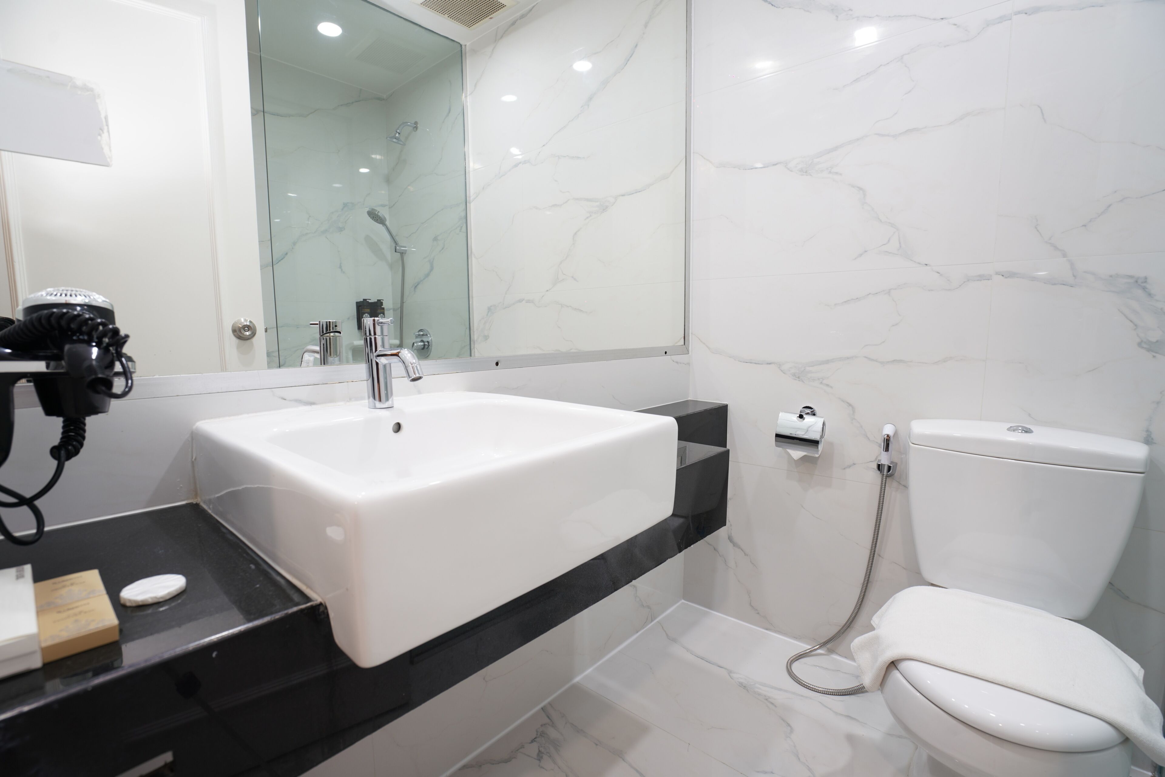 A bathroom with a white sink, a mirror, a toilet, and a shower area.
