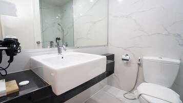 A bathroom with a white sink, a mirror, a toilet, and a shower area.