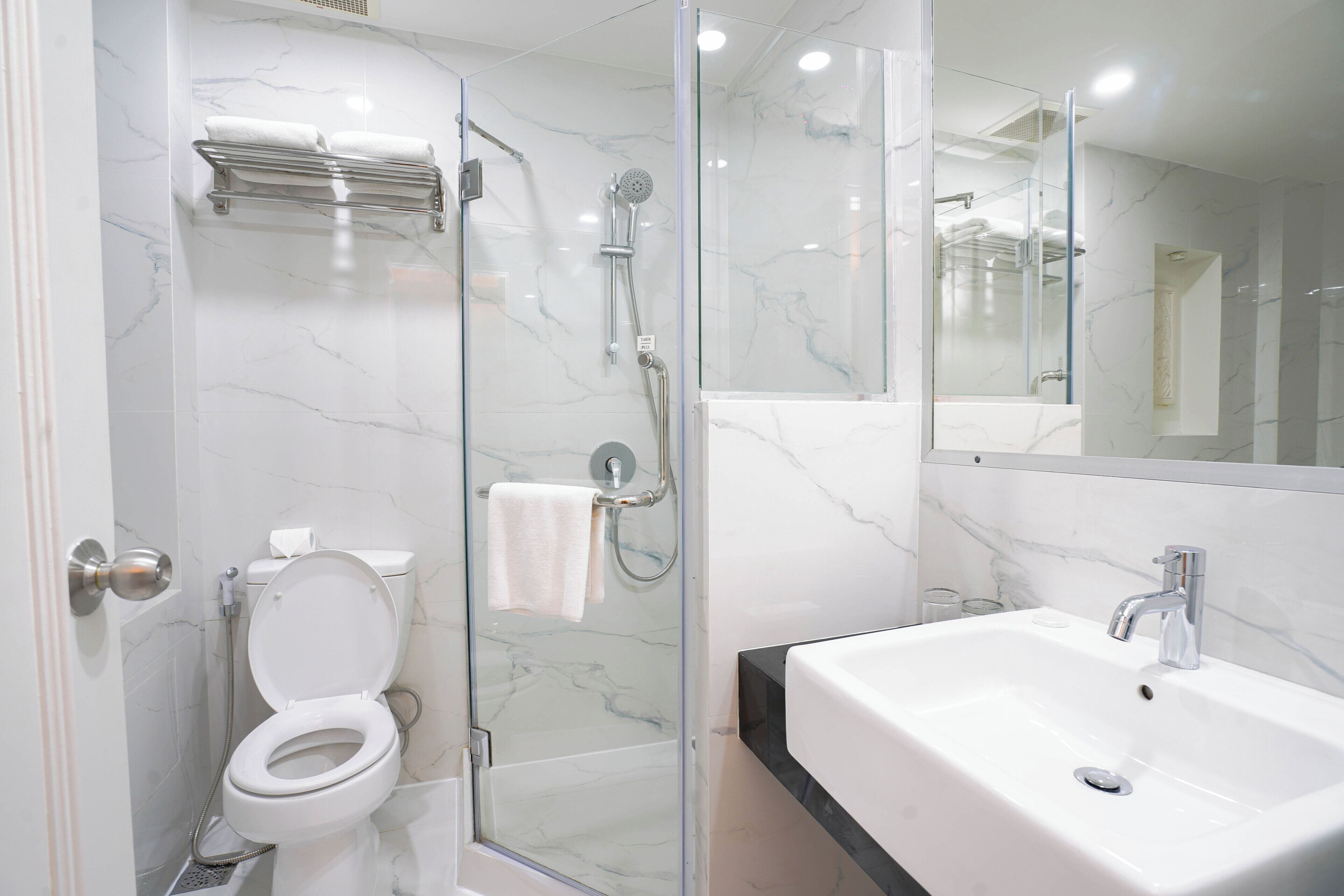A modern bathroom with a glass-enclosed shower, a white toilet, and a large sink.
