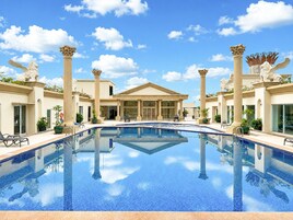 A hotel with a central swimming pool, columns, and statues.