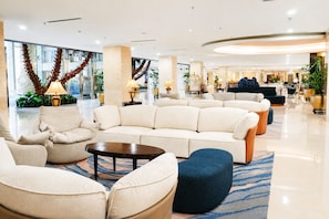 A hotel lobby with a large sofa, armchairs, a coffee table, and a blue ottoman. - Harmoni One Convention Hotel & Service Apartments (Batam)