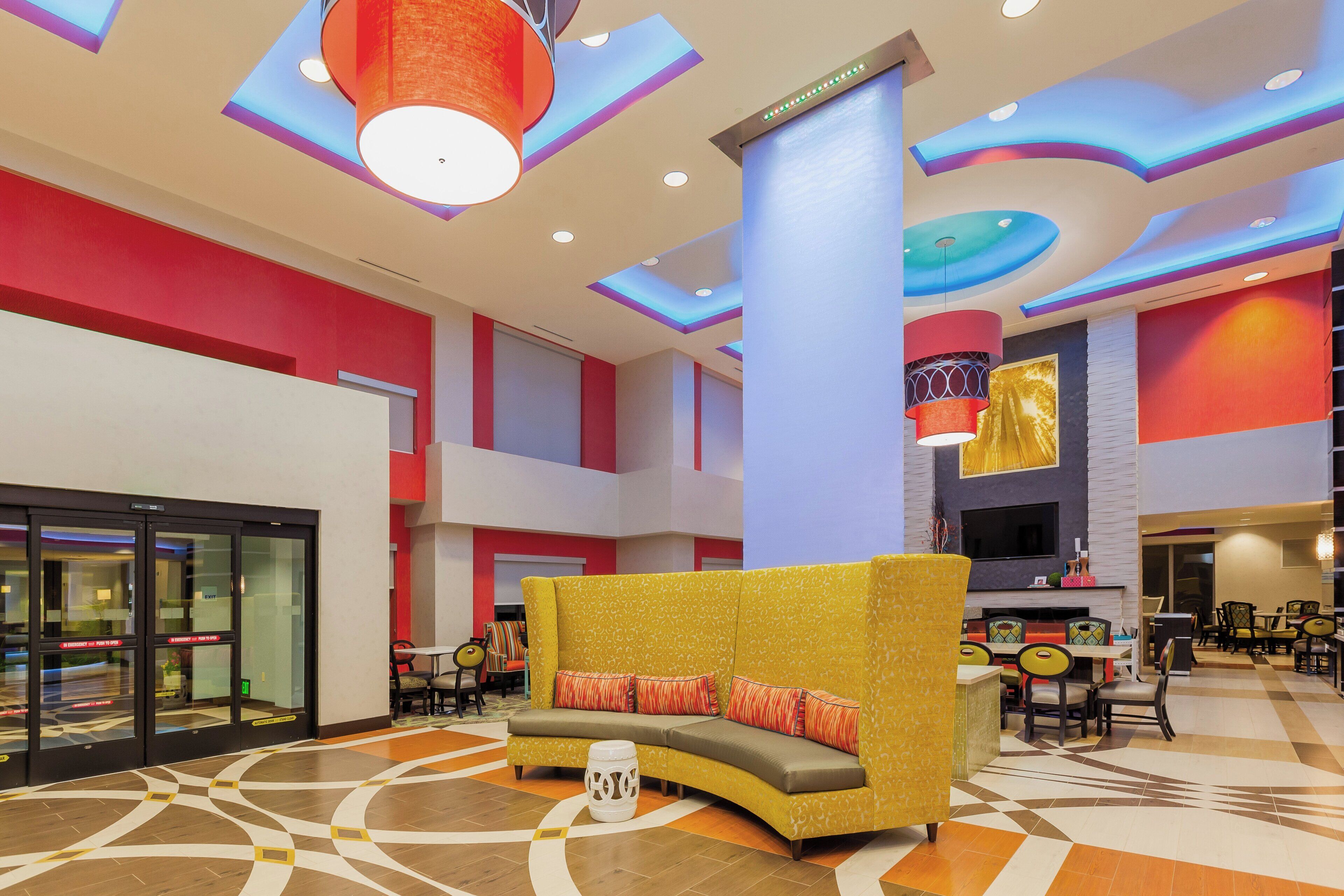 A spacious lobby with a curved yellow sofa, a patterned floor, and a modern ceiling design.