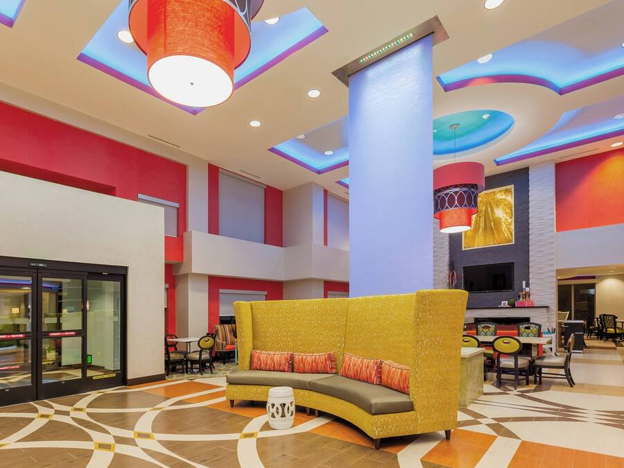 Een ruime lobby met een gebogen gele bank, een patroon vloer en een modern plafondontwerp.