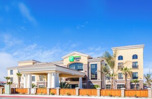 Un hôtel Holiday Inn Express avec une structure à deux étages, de grandes fenêtres et un espace extérieur couvert.