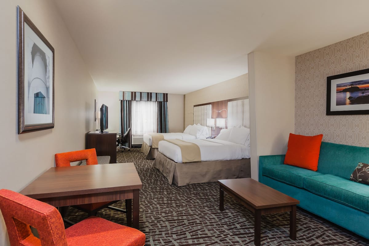 A hotel room with a bed, a sofa, a desk, and a chair.