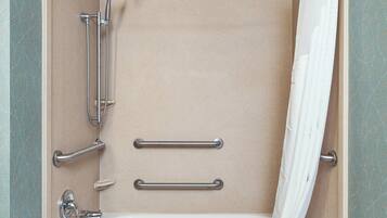 A modern bathroom with a bathtub, grab bars, and a shower head.