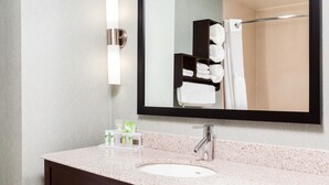 A bathroom with a large mirror, a sink, and a towel rack.