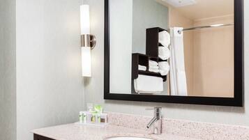 Une salle de bain équipée d’un lavabo, d’un miroir, d’un porte-serviettes et d’articles de toilette.