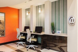 A modern office space with a desk, two chairs, a computer, and a decorative plant.