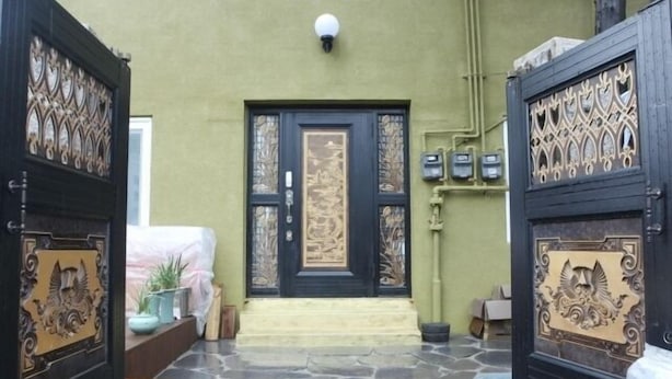 Entrada de un edificio con una puerta negra, detalles de metal ornamentado y un panel central.