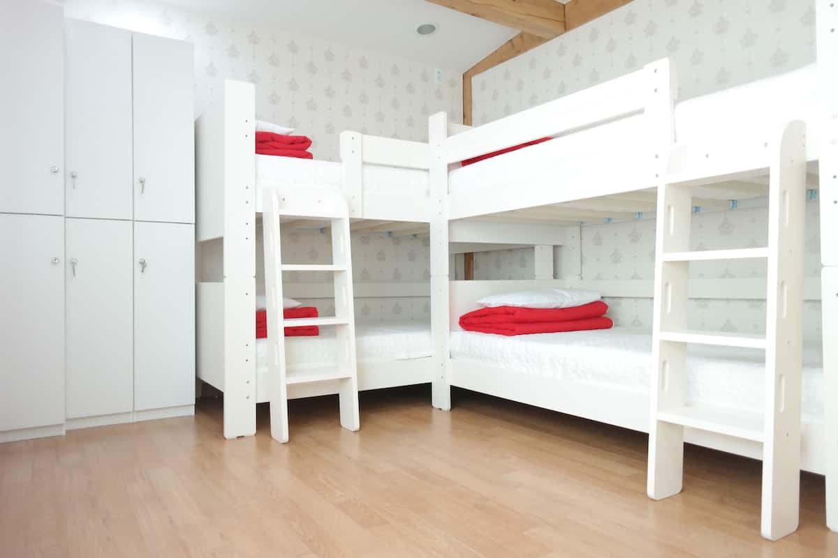 Una habitación con literas, un armario y suelo de madera.