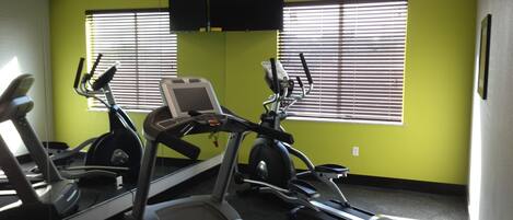 Ein Fitnessstudio mit Laufbändern, Crosstrainern und einem Ergometer.