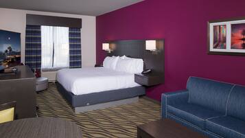 Quarto de hotel com cama, escrivaninha, sofá e mesa de cabeceira com luminárias.