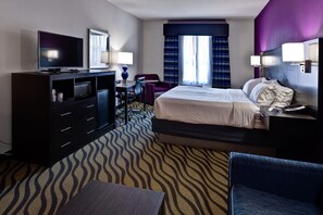 A hotel room with a bed, a desk, a television, a chair, and a desk lamp. - Holiday Inn Express Hutchinson by IHG (Hutchinson)