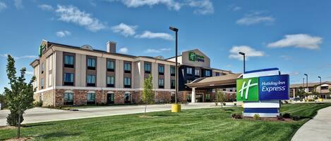 A Holiday Inn Express hotel with a modern design, featuring a brick facade and a clear blue sky.