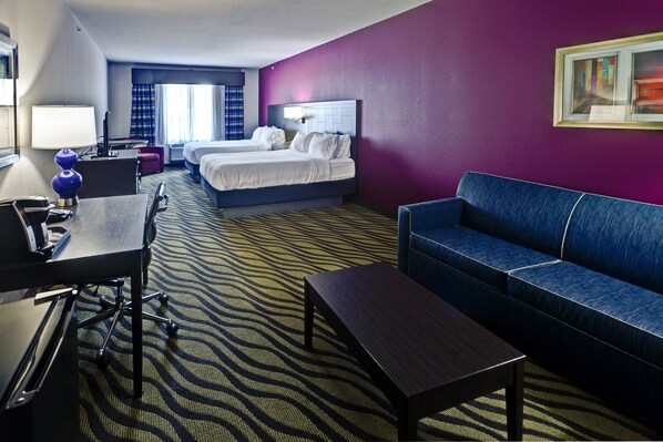A hotel room with two beds, a desk with a lamp, a blue sofa, and a patterned carpet. - Holiday Inn Express Hutchinson by IHG (Hutchinson)