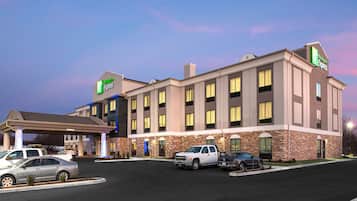 A Holiday Inn Express hotel with a parking lot, multiple vehicles, and a clear sky.