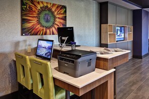 A reception desk with a computer, printer, and seating area. - Holiday Inn Express Hutchinson by IHG (Hutchinson)