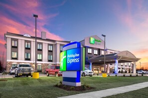 Un hôtel Holiday Inn Express doté d’une façade moderne, d’une enseigne bien visible et d’un parking où sont stationnés plusieurs véhicules.