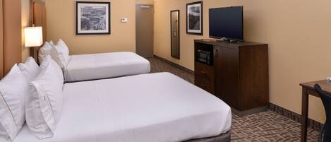 A hotel room with two beds, a television on a cabinet, and framed pictures on the wall.