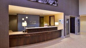 A hotel reception desk with a modern design, a digital screen above, and a sign indicating the hotel name. - Holiday Inn Express & Suites Page - Lake Powell Area by IHG (Page)