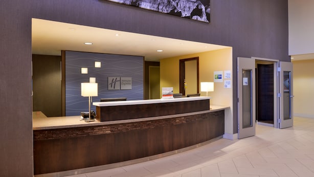 Un mostrador de recepción de hotel con un diseño moderno, una pantalla digital en la parte superior y un cartel con el nombre del hotel.