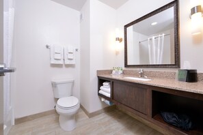 A modern bathroom with a white toilet, a sink with a mirror above it, and a shower curtain. - Holiday Inn Express & Suites Page - Lake Powell Area by IHG (Page)