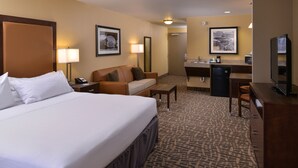 A hotel room with a large bed, a sofa, a desk, a television, and a small kitchenette. - Holiday Inn Express & Suites Page - Lake Powell Area by IHG (Page)
