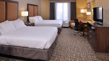 A hotel room with two beds, a desk, a television, and a chair.