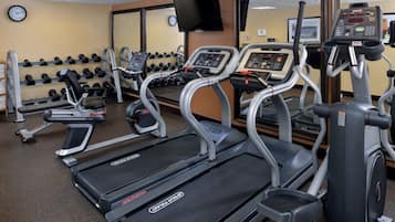 Ein Fitnessstudio mit Laufbändern, Crosstrainern und Gewichtsständern.