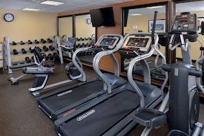 A gym with treadmills, elliptical machines, and weight racks.