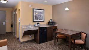 Una habitación de hotel compacta con kitchenette, comedor y cama.