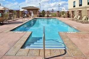A rectangular swimming pool with a clear blue water surface, surrounded by a stone deck and lounge chairs. - Holiday Inn Express & Suites Page - Lake Powell Area by IHG (Page)
