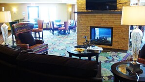 A hotel lobby with a fireplace, seating area, and a television mounted on the wall.