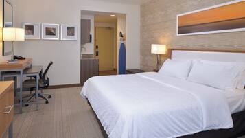 Habitación de hotel con cama, escritorio, silla y baño visible a través de una puerta abierta.