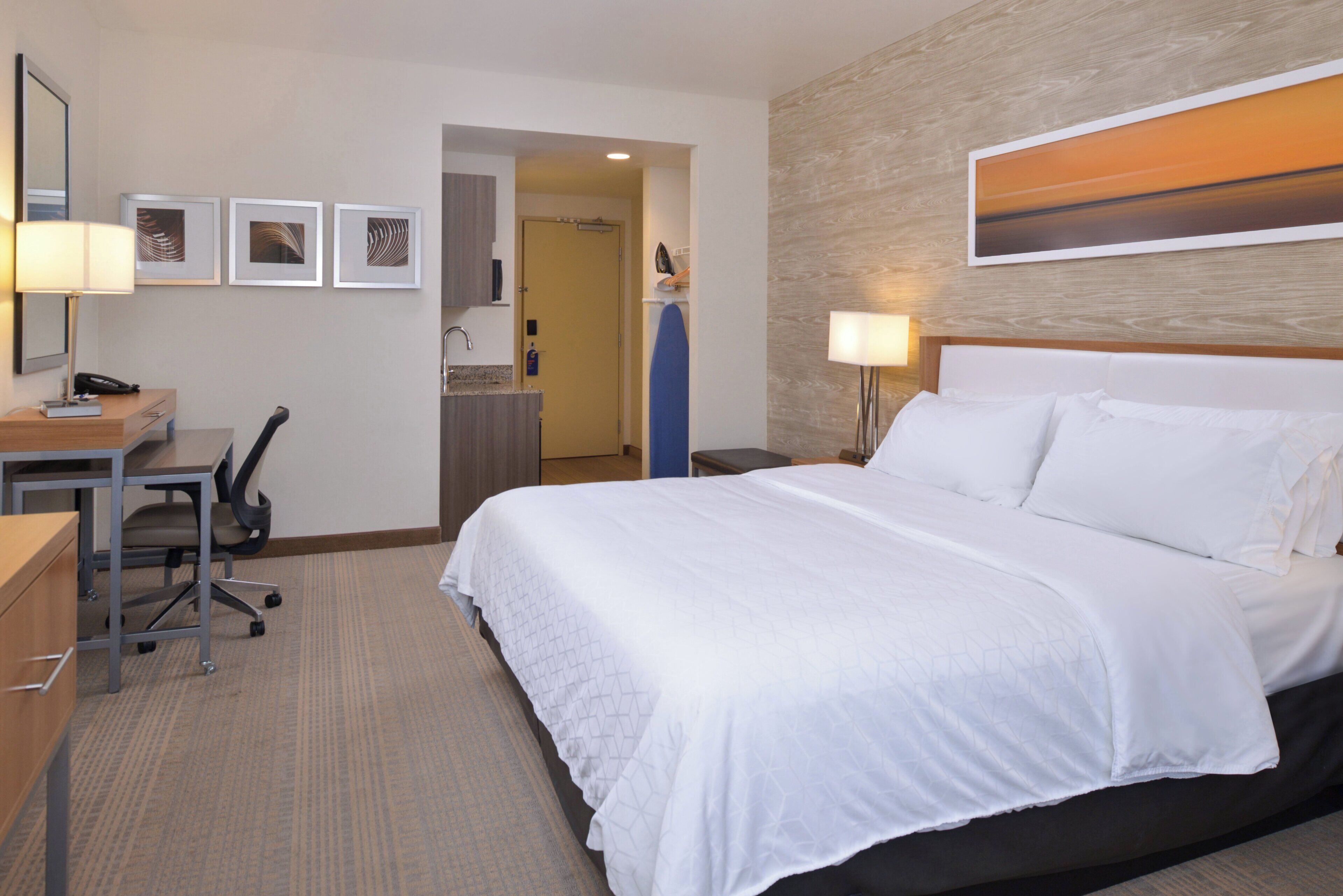 A hotel room with a bed, desk, chair, and a bathroom visible through an open door.