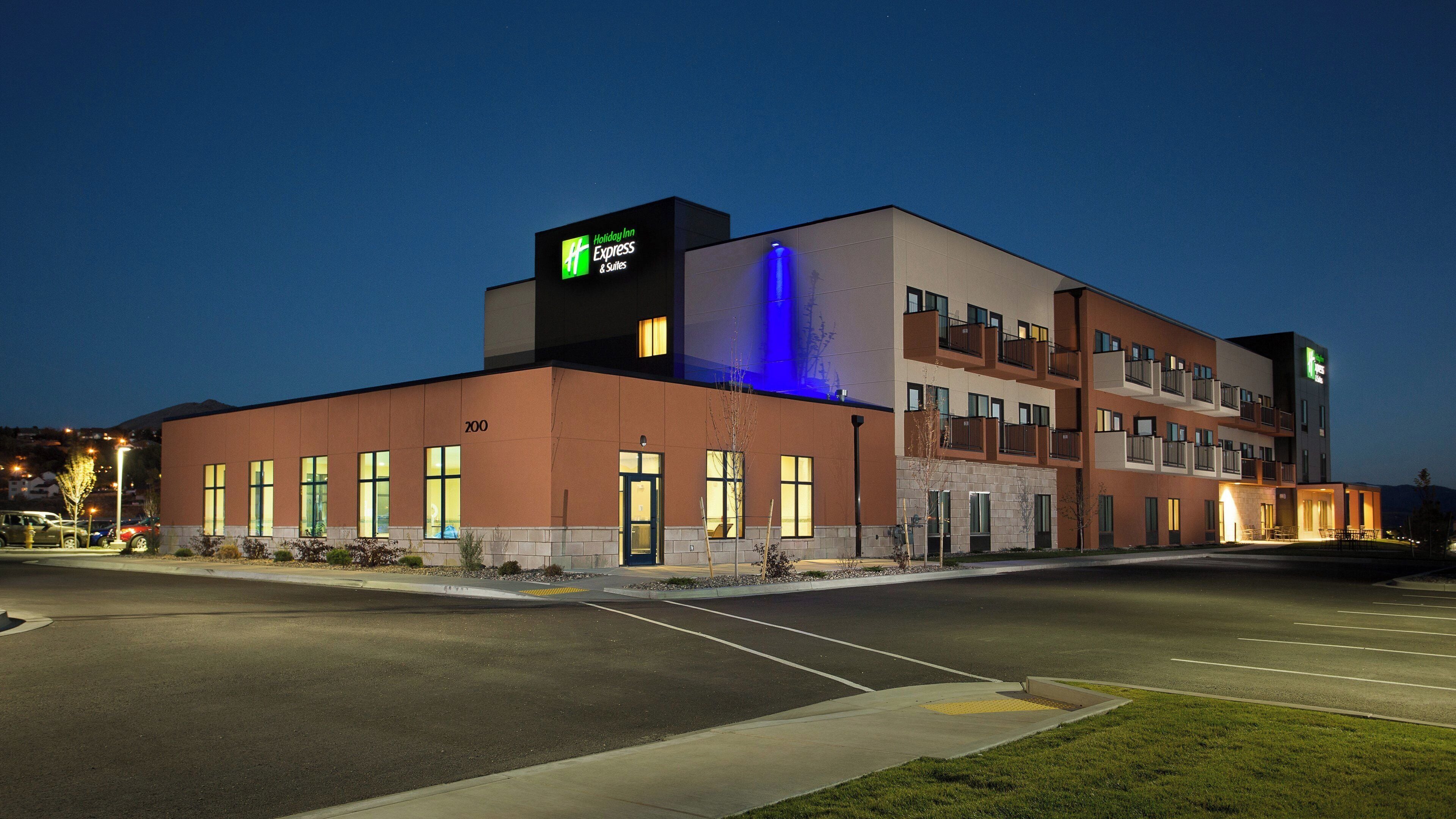 Un hotel Holiday Inn Express con un diseño moderno, que presenta un techo plano, varios balcones y una fachada bien iluminada.