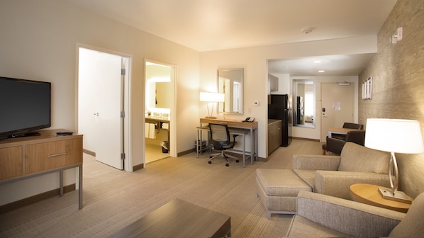 Une chambre d’hôtel équipée d’une télévision, d’un bureau, d’une chaise, d’un canapé et d’une lampe.