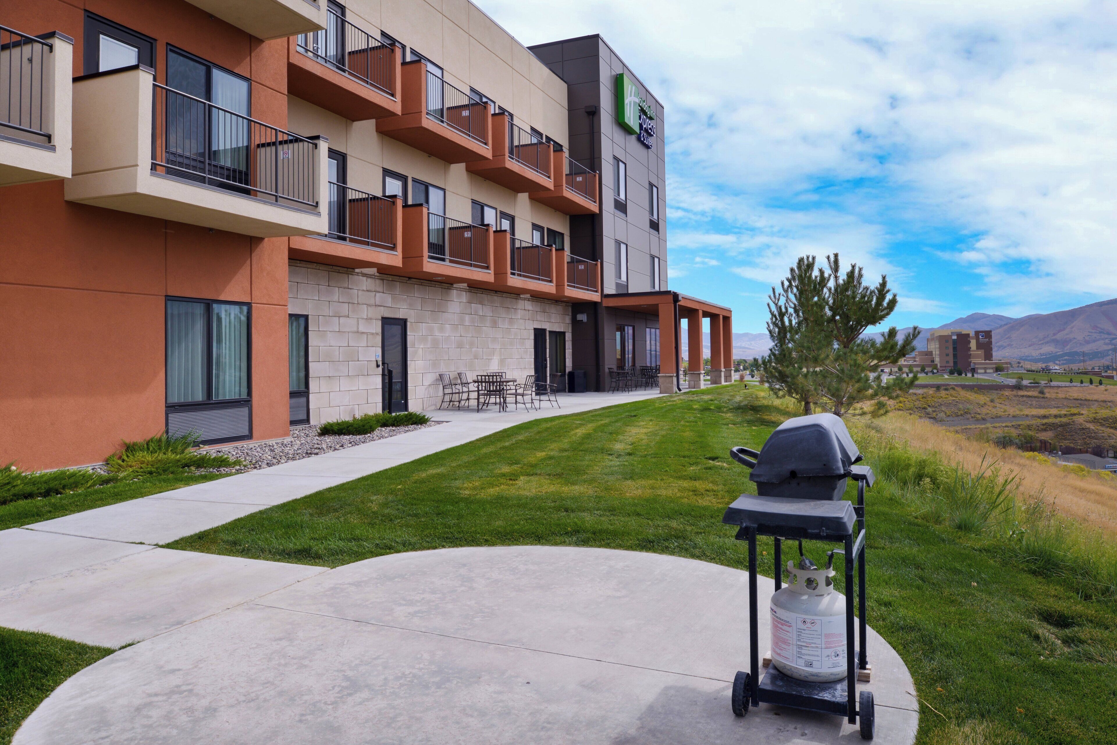 A modern hotel with a patio area, outdoor seating, and a grill.