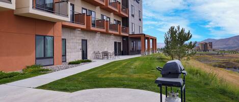 A modern hotel with a patio area, outdoor seating, and a grill.