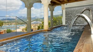 An indoor swimming pool with a view of mountains and a marina. - Hotel Villa Italia (Andraitx)