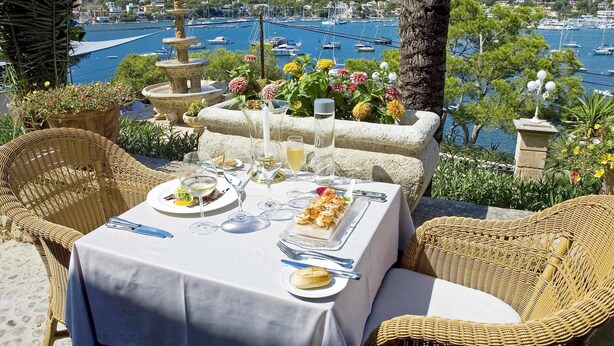 A table set for a meal with a view of a marina and hills in the background. - Hotel Villa Italia (Andraitx)