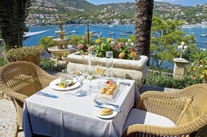 A table set for a meal with a view of a marina and hills in the background. - Hotel Villa Italia (Andraitx)
