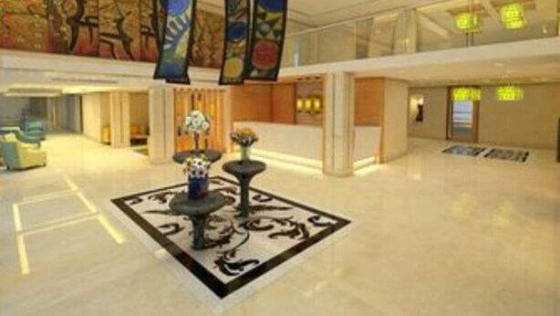 A spacious lobby with a high ceiling, decorative banners, a central floral arrangement, and a modern design. - Lemon Tree Hotel Shimona (Chennai)
