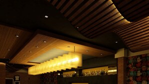 A bar area with a long counter, multiple stools, and a variety of bottles and glasses. - Lemon Tree Hotel Shimona (Chennai)