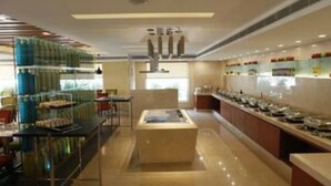 A modern hotel lobby with a long buffet line, a central seating area, and a glass partition on one side. - Lemon Tree Hotel Shimona (Chennai)