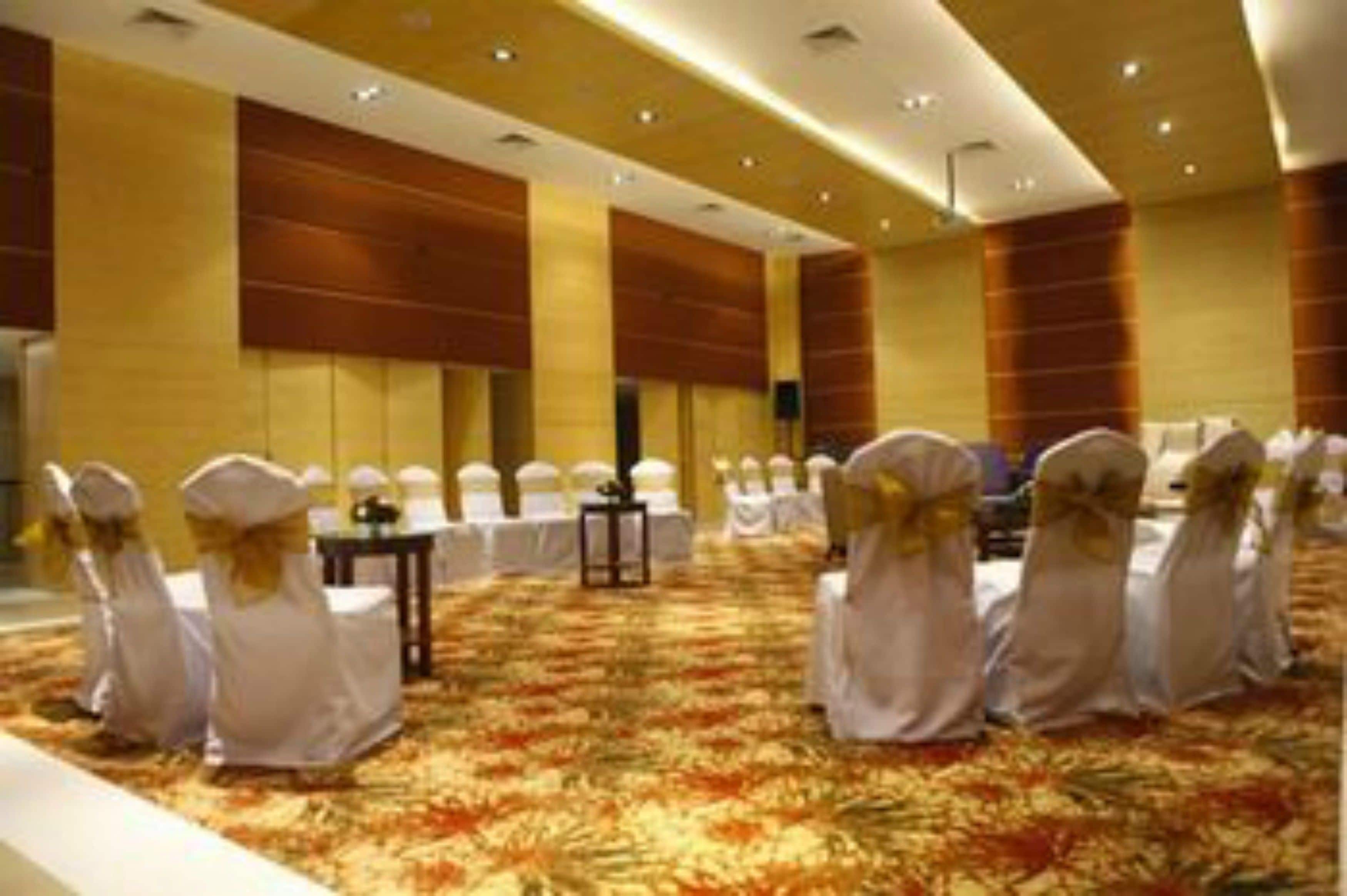 A conference room with rows of white chairs and a carpeted floor.