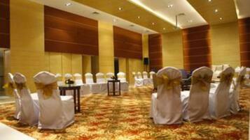 A conference room with rows of white chairs and a carpeted floor.